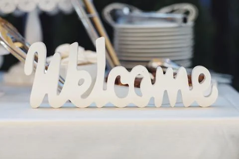 White cursive "Welcome" sign sits atop a table Fotos de archivo