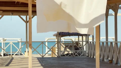 White Curtains Flutter in Breeze on Empty Beach Terrace by Calm Blue Ocean Video stock 335170543