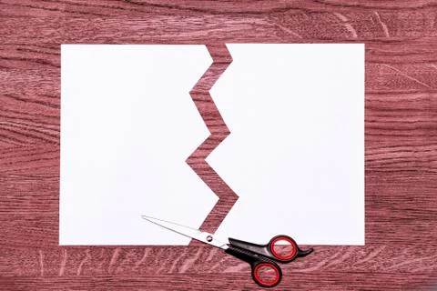 White cut sheet and scissors. Background of pinkish brown wood. Stock-Fotos