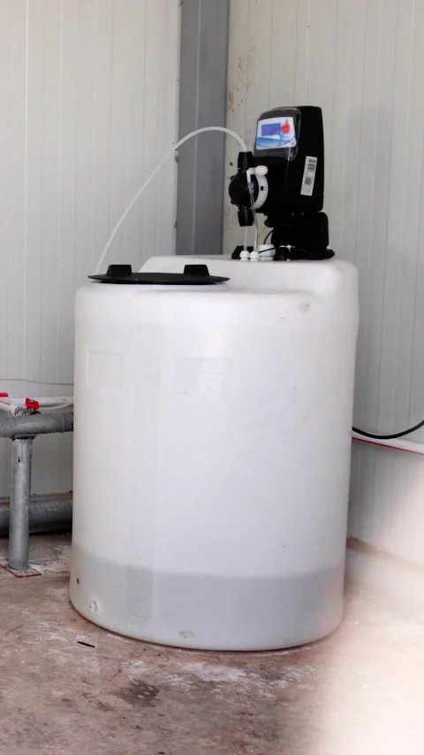 White cylindrical tank with black pump and control panel, positioned in a clean Stockbeeldmateriaal 338397948