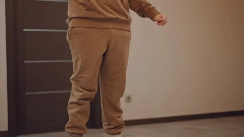 White dancer practicing squat and footwork, sneakers tapping on laminate floor Stock Footage 346552761