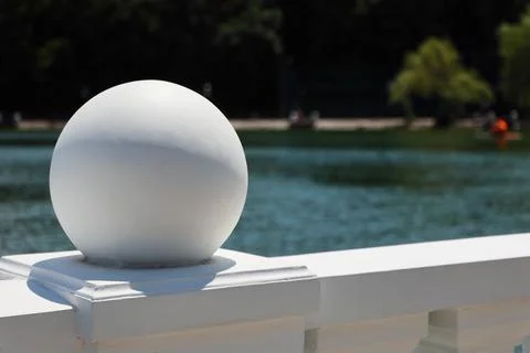 White decorative stone sphere on a railing with blurred lake background Foto stock