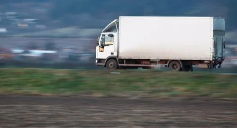 White delivery truck going fast on a road (panned image - motion Stock Photos