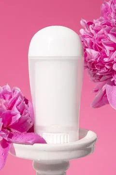 White deodorant on podium on pink background with peony flowers. Stock Photos