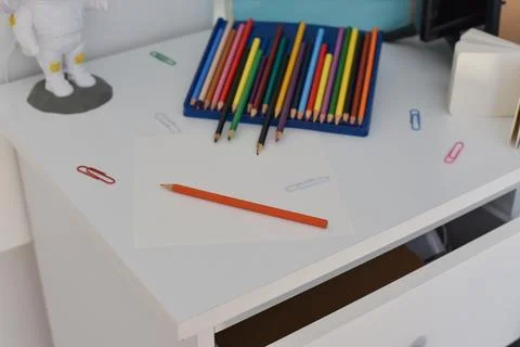 White desk blue tray colored pencils orange pencil on paper colorful paper clips Foto stock