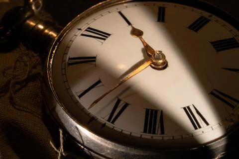 The white dial of an antique silver pocket watch with minute and hour hands Stock Photos