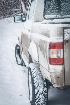 A white dirty SUV covered with a layer of snow. A car for off-road and extreme Stock Photos