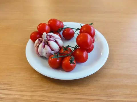 White dish with bunch of mini tomatoes and garlic. Foto stock