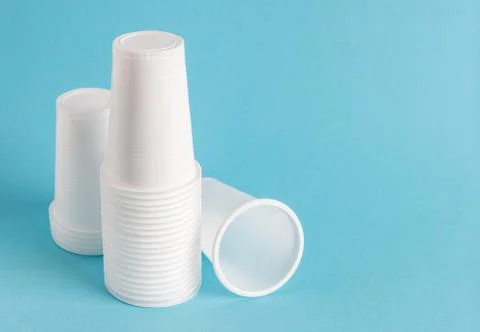 White disposable plastic cups on a blue background with copy space Stock Photos