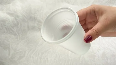White disposable plastic cups for drinks in a womans hand. The use of disposable Stock Footage 317094265