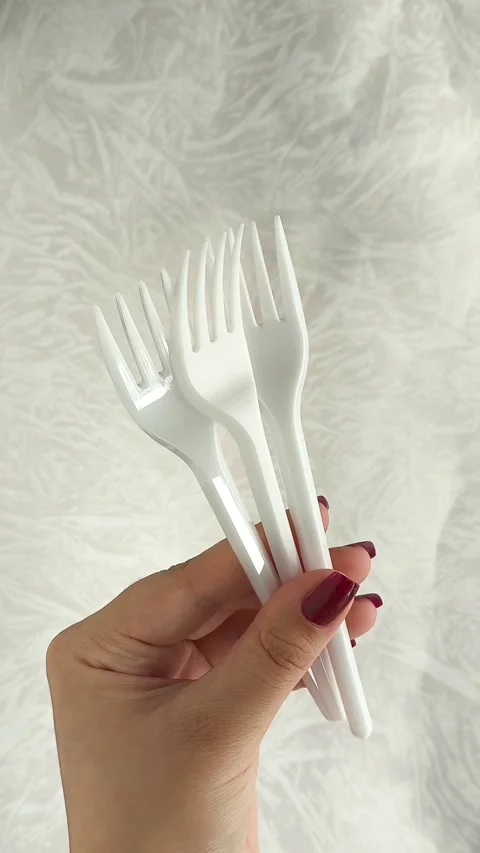 White disposable plastic forks in a womans hand. The use of disposable tableware Stock Footage 317093710