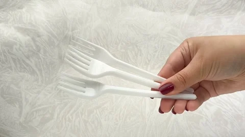 White disposable plastic forks in a womans hand. The use of disposable tableware Stock Footage 317094064