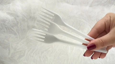 White disposable plastic forks in a womans hand. The use of disposable tableware Stock Footage 317094197