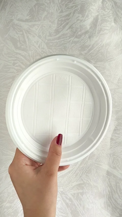 White disposable plastic plates in a womans hand. The use of disposable Stock Footage 317093775