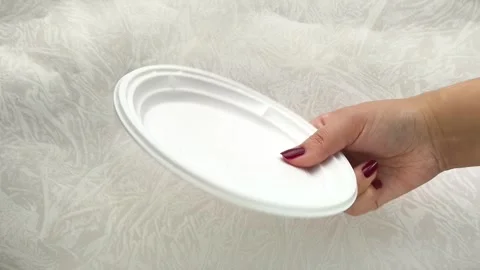 White disposable plastic plates in a womans hand. The use of disposable Stock Footage 317094082