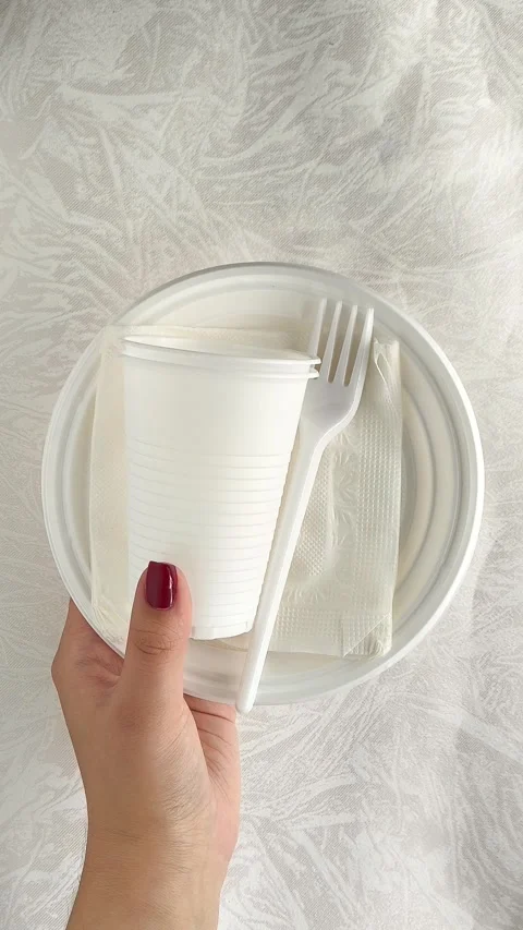 White disposable plastic tableware set in a womans hand. The use of disposable Stock Footage 317093420