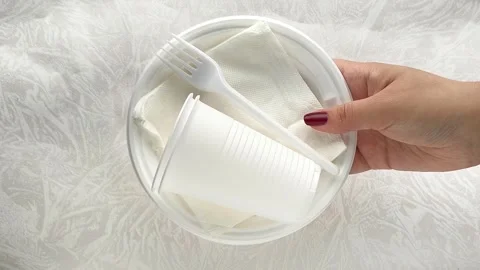 White disposable plastic tableware set in a womans hand. The use of disposable Stock Footage 317094282