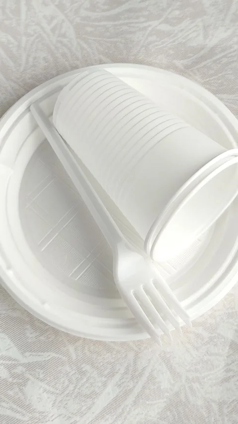 White disposable plastic tableware set on the table. The use of disposable Stock Footage 317669185