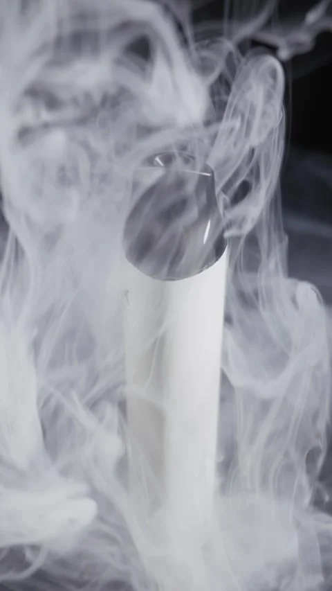 White Disposable Vape Pen Rotating in Billowing White Smoke Video stock 329607020