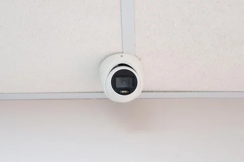 White dome security camera installed on tiled ceiling Stock Photos