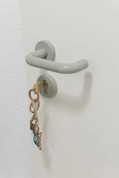 White door handle with a key ring on a white wall background. Stock Photos
