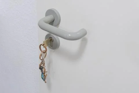 White door handle with a key ring on a white wall background. 写真素材