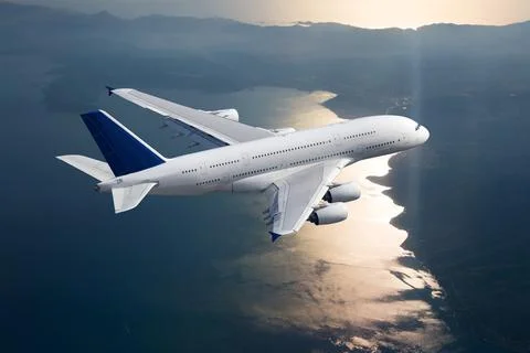 White double decker passenger plane in flight. Aircraft fly above the sea. Stock Photos