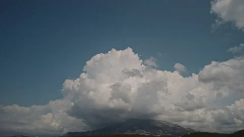 White dramatic clouds, cumulus, forming over the mountain peak with blue sky in Stock Footage 171813938