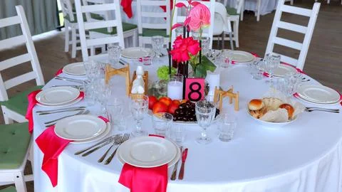 White draped banquet table featuring floral centerpiece, fresh fruits, glowing Foto stock