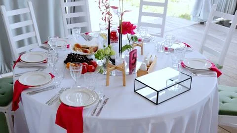 White draped round table featuring floral centerpiece, scattered fruits Stock Photos