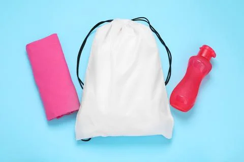 White drawstring bag, bottle and cloth on light blue background, flat lay Stock Photos
