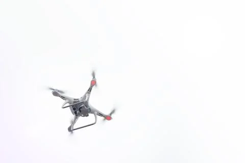 White Drone with Camera Flying in Blue Sky. UAV Concept Stock Photos