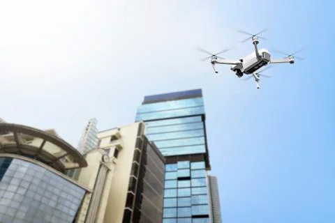 White drone with camera flying to the top of modern building Fotos de archivo