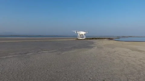 White drone flying above sandy coast followed by second unmanned aerial vehicle Stock Footage 339392839