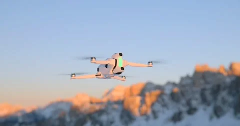 White Drone Hovering with Snowy Mountains in Background at Sunset Stock Footage 343928162