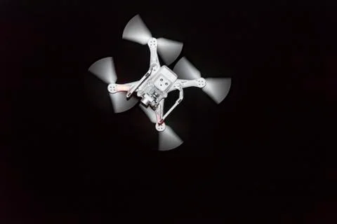 White drone with working propellers isolated on black background Stock Photos