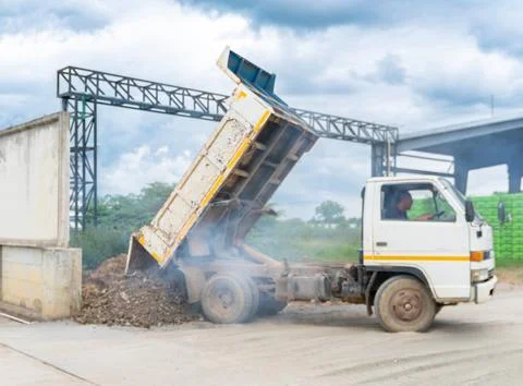 White dump truck unloading soil and gravel at an outdoor construction site .. Stock Photos