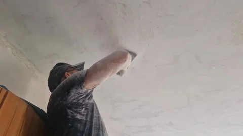 White dust falls in clouds as man sands ceiling by hand during renovation 스톡 동영상 313486798