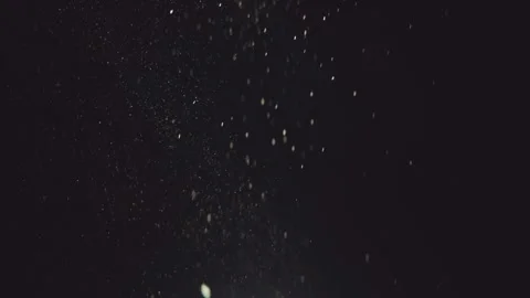 White dust particles falling slowly through light on black background. Stock Footage 344998682