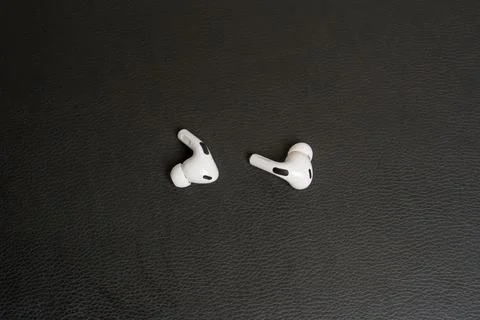 White earbuds rest on dark textured surface Stock Photos