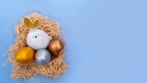A white Easter bunny with multicolored painted eggs sitting in a homemade n.. 스톡 사진
