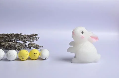 White Easter Bunny. White and yellow eggs. Lavender. Easter. Light purple bac Stock Photos