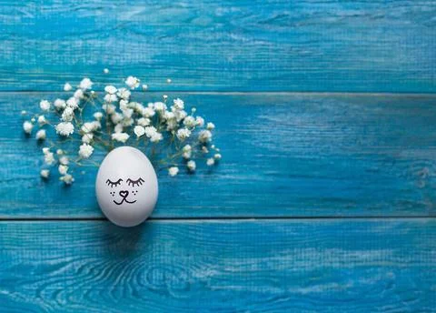 White easter egg with drawn cute face, decoreted with gypsophila flowers Foto stock