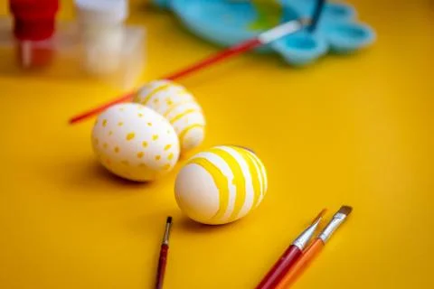 White easter egg with yellow dots and line painted with brush. Stock Photos
