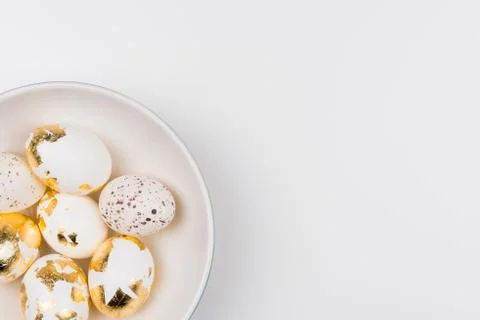 White Easter eggs decorated with golden foil in white bowl. Easter concept. Stock Photos