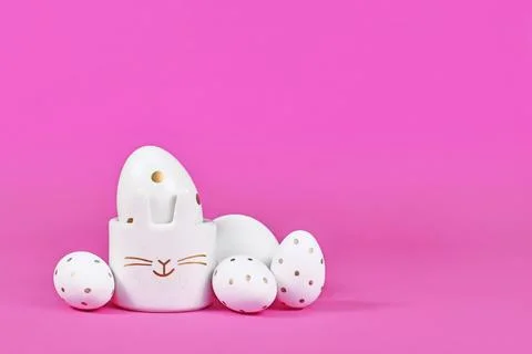 White Easter eggs with golden dots and cute egg cup in shape of bunny on pink Stock Photos