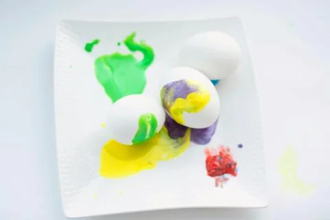 White Easter eggs, lying on a white plate, with multicolored colors. Stock Photos