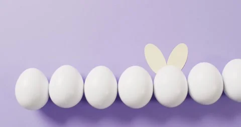 White easter eggs with rabbit ears on purple background with copy space Stock Footage 331211046