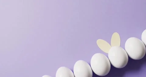 White easter eggs with rabbit ears on purple background with copy space Stock Footage 331246019