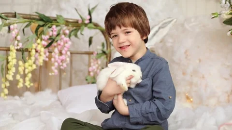 White Easter rabbit sits on the hands of a little boy, who huggs the rabbit Stock Footage 264170933